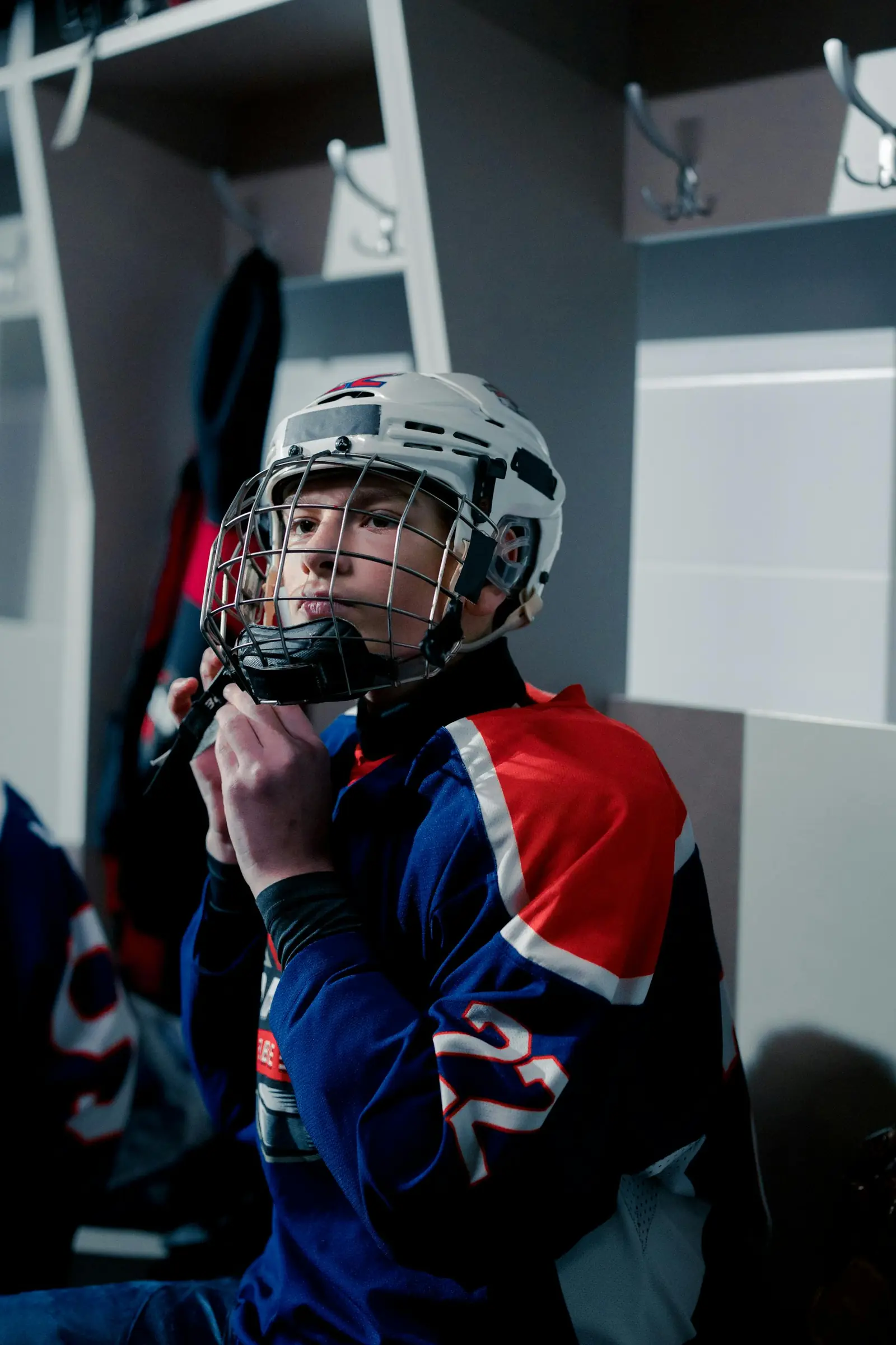 A young hockey player buckling his helmet in the locker room